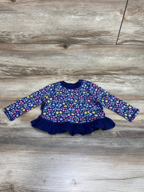 Flat lay of Cat & Jack baby peplum shirt showcasing floral print, long sleeves, and ruffled hem on wood surface