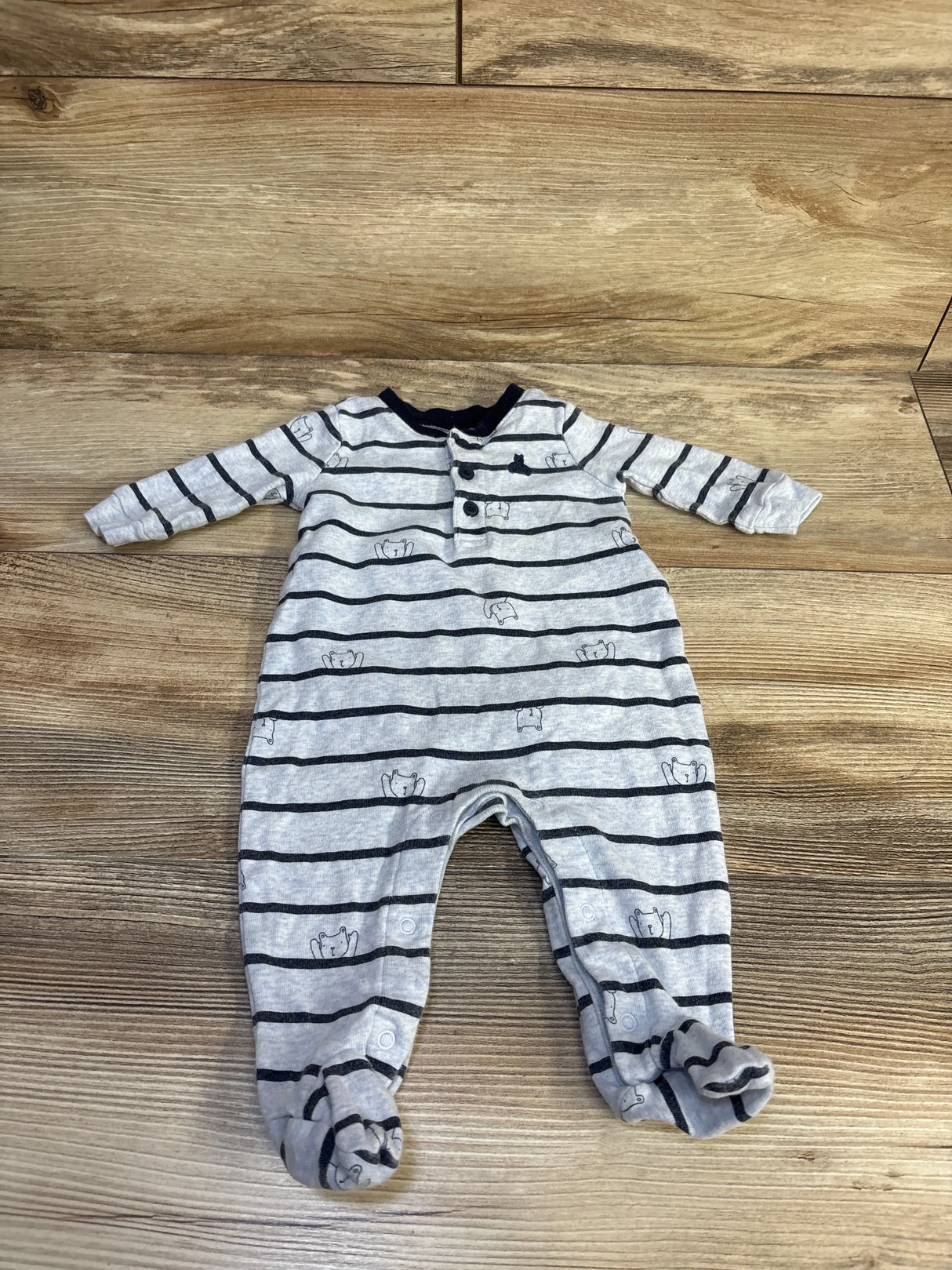 Flat lay of Baby Gap blue striped newborn coverall showing navy stripes, bear face prints, front snaps and footed legs on wooden floor