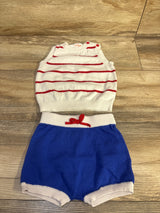 Flat lay of Cat & Jack 2pc knit baby set showing white sleeveless sweater with red stripes and blue knit shorts on wood floor