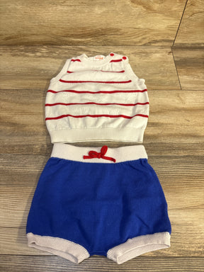 Flat lay of Cat & Jack 2pc knit baby set showing white sleeveless sweater with red stripes and blue knit shorts on wood floor