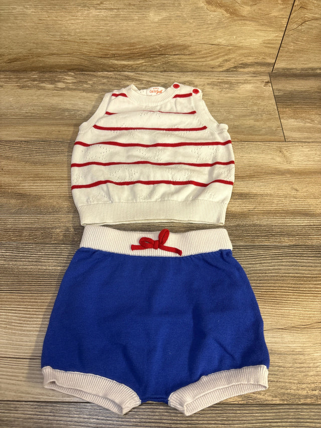 Flat lay of Cat & Jack 2pc knit baby set showing white sleeveless sweater with red stripes and blue knit shorts on wood floor