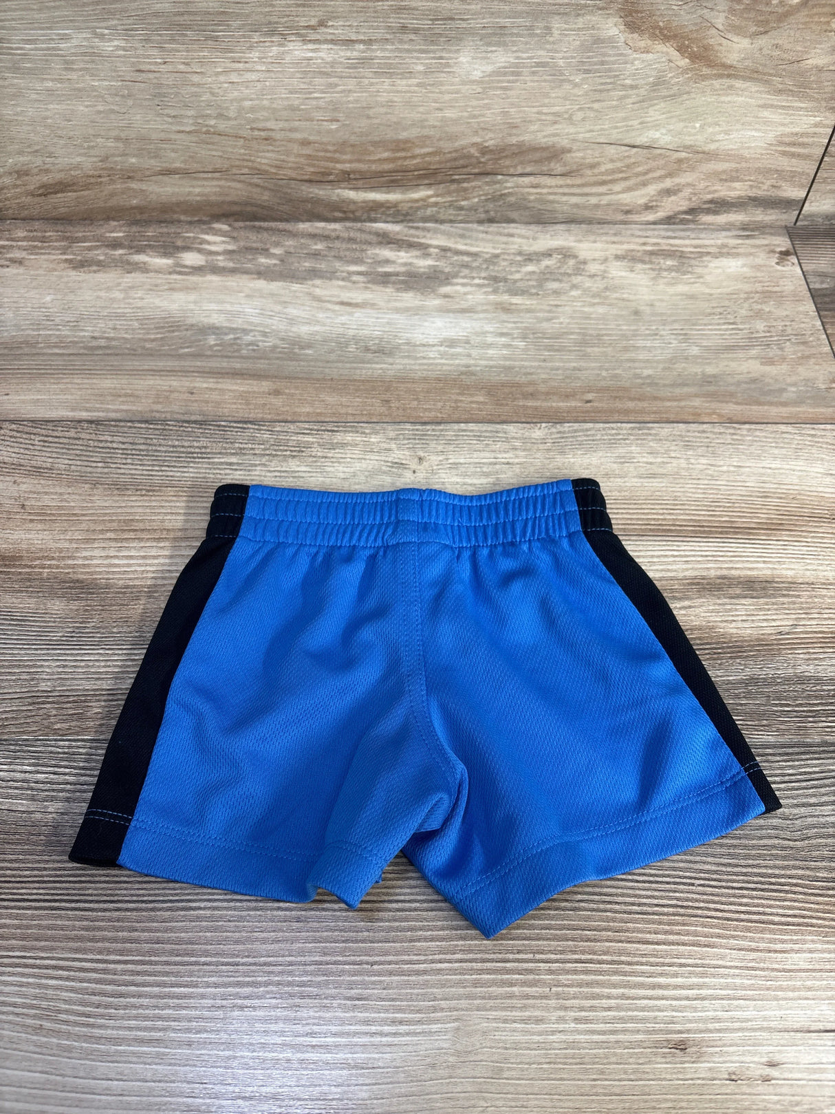 Flat-lay of blue Hurley toddler active shorts showing elastic waistband and black side panels on light wood background