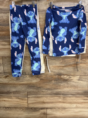 Front view of toddler 4-piece pajama set with navy Stitch print top and matching pants plus beige pieces on wood floor