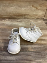 Front three quarter view of Teeny Toes First Walker baby shoes size 4C, white lace up with padded ankle and flexible sole on wooden surface