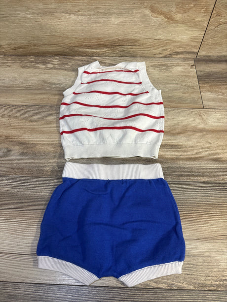 Flat lay baby knit 4th of July set: white sleeveless top with red stripes and blue knit shorts with white waist on wood floor