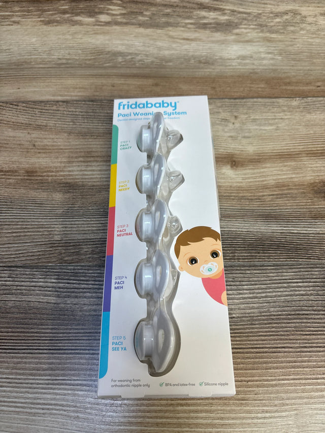 Top-down view of FridaBaby Paci Weaning System 5 pack showing five staged orthodontic silicone pacifiers in clear blister packaging on a wood table