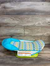 Angled view of Summer Deluxe baby bather in green showcasing mesh sling and molded head support on a white bathtub background