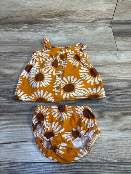 Flat lay of Carter's two-piece sunflower top and matching shorts showing front buttons and elastic-waist bloomers on wood floor, size 3M