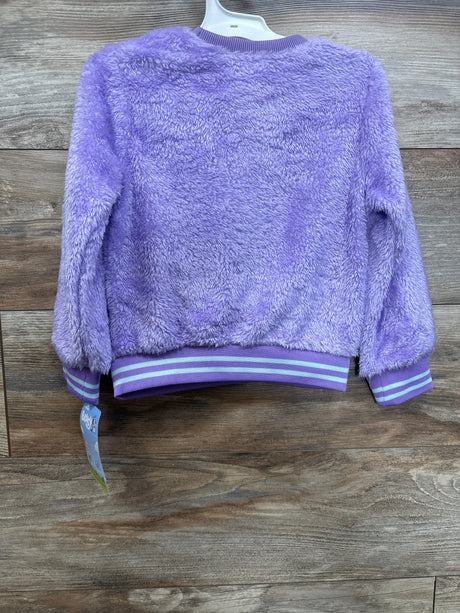 Purple fuzzy kids jacket with striped cuffs and waistband on wood background