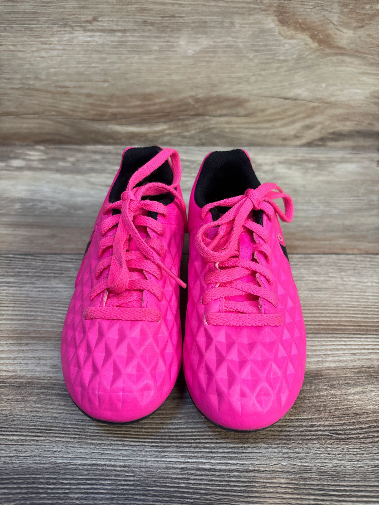 Bright pink kids' soccer cleats with textured design, ideal for young athletes