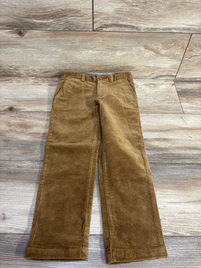 Brown corduroy kids pants with pockets, laid flat on wooden floor