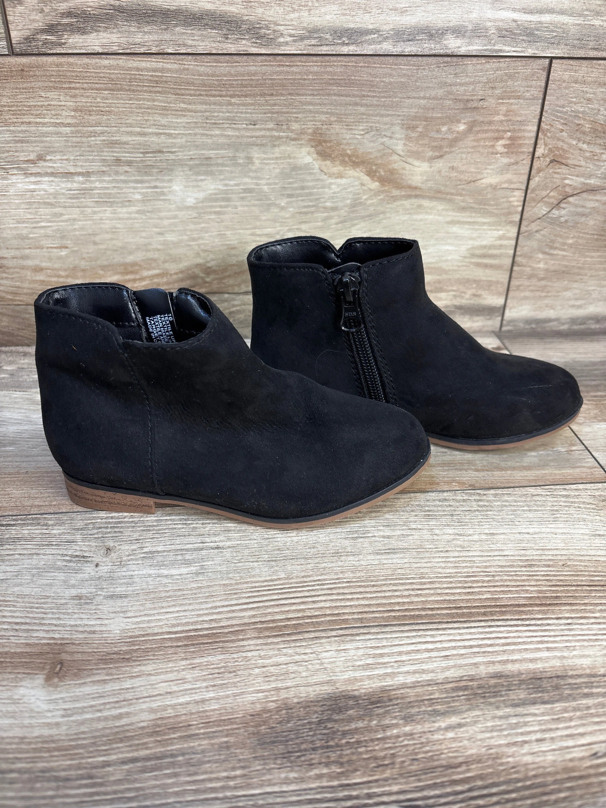 Black suede ankle boots for kids with side zipper on wooden background