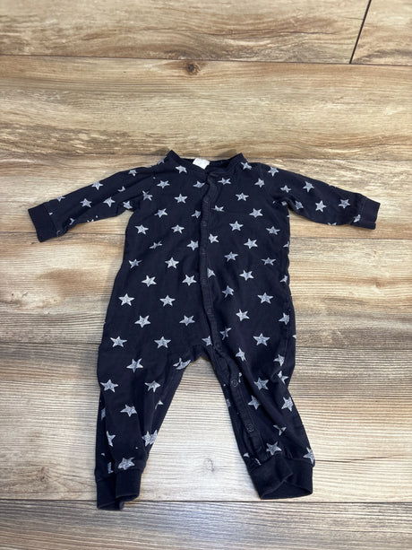 Black baby sleeper with white star print and snap buttons on wood floor