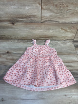 Top down view of pink floral tiered toddler dress with ruffled shoulder straps on wood plank background