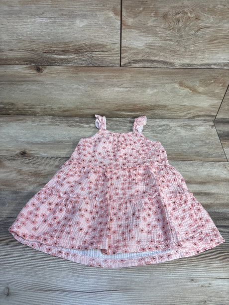 Top down view of pink floral tiered toddler dress with ruffled shoulder straps on wood plank background