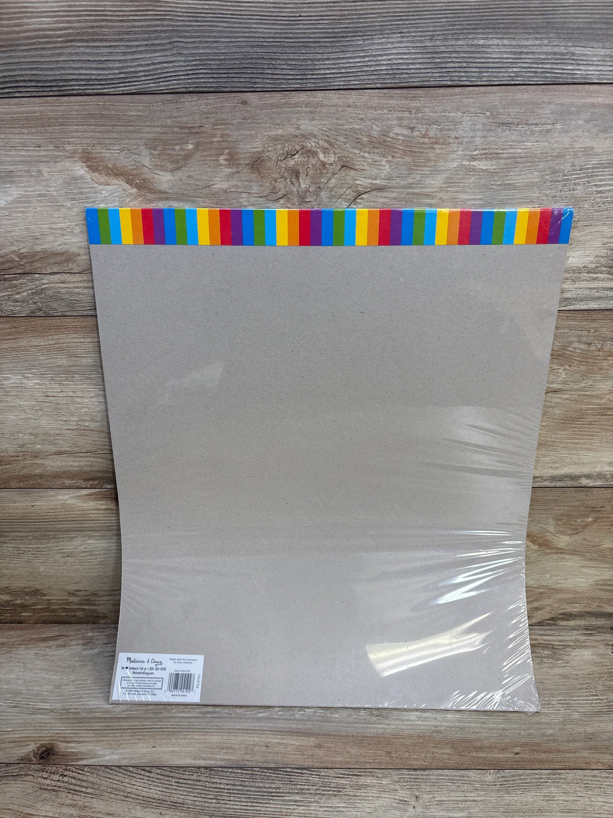 Pack of blank poster boards with colorful striped edge on a wood background