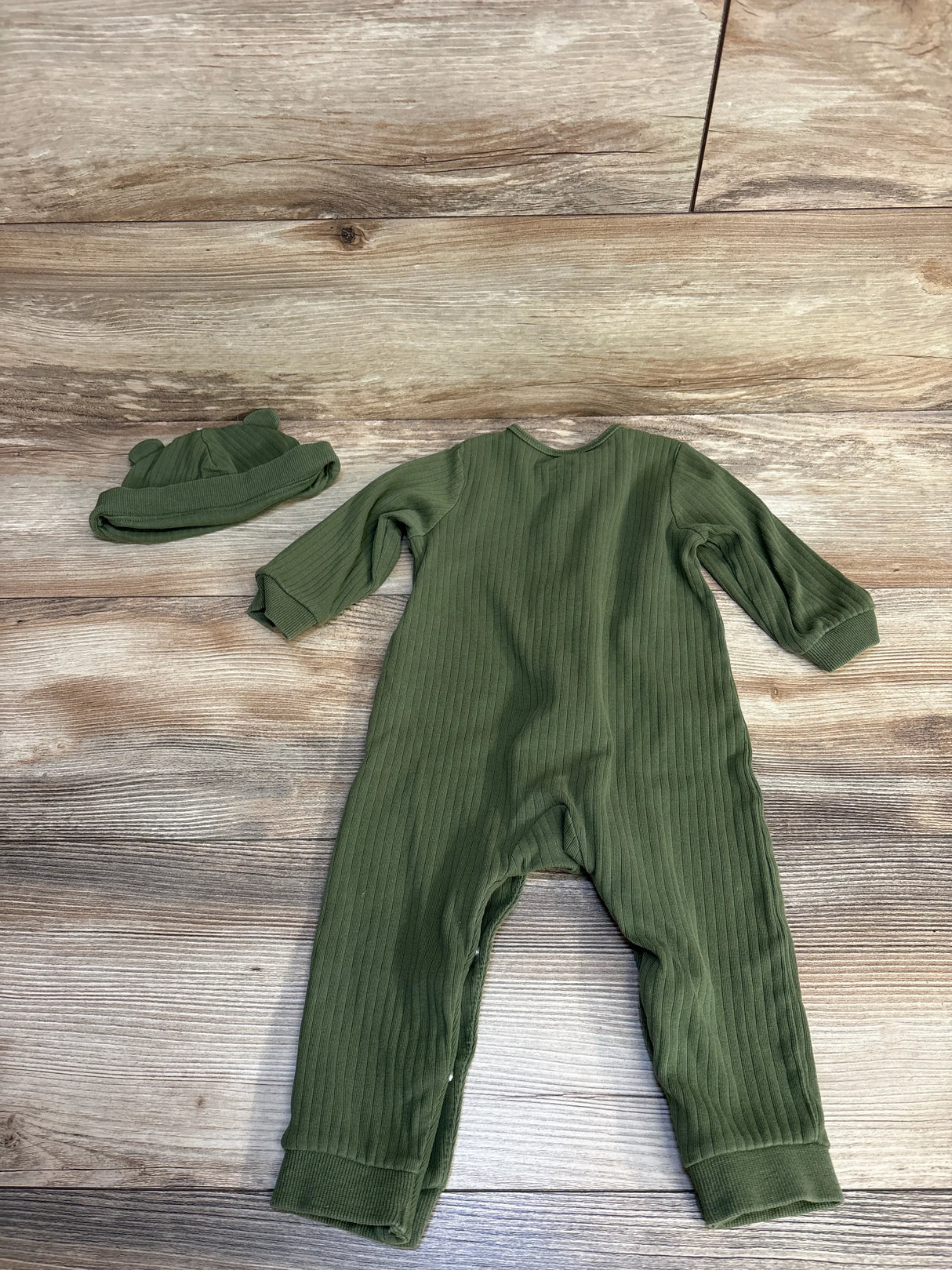 Olive green ribbed baby romper and matching hat with bear ears on wood background