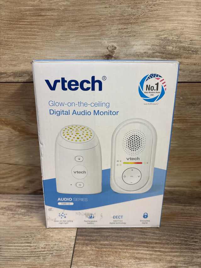 Front view of VTech TM8112 boxed digital audio baby monitor showing glow-on-the-ceiling night light graphic and parent unit on wood background