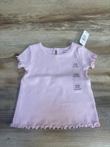 Light pink baby short sleeve shirt with ruffled hems, size 6-12 months, on wood background