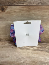 Rear view of large galaxy purple hair bow with tie-dye pattern and silver alligator clip on white card and wood background