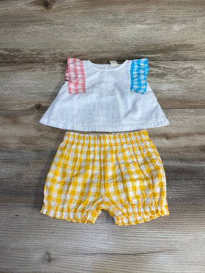 Flat lay of Tucker and Tate baby ruffle top with multicolor gingham sleeves and yellow gingham shorts on wood background