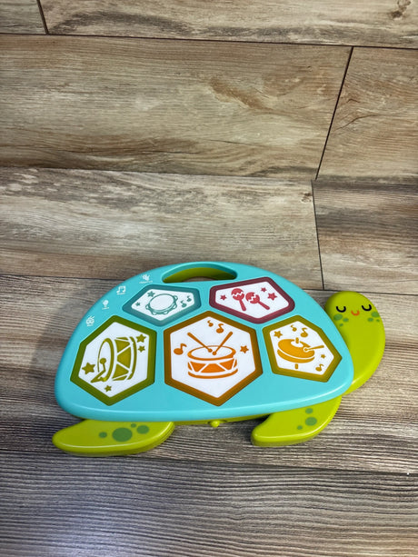 Top-down view of Gigglescape Turtle electronic drum showcasing five light-up hexagon drum pads and smiling turtle handle on wood floor background