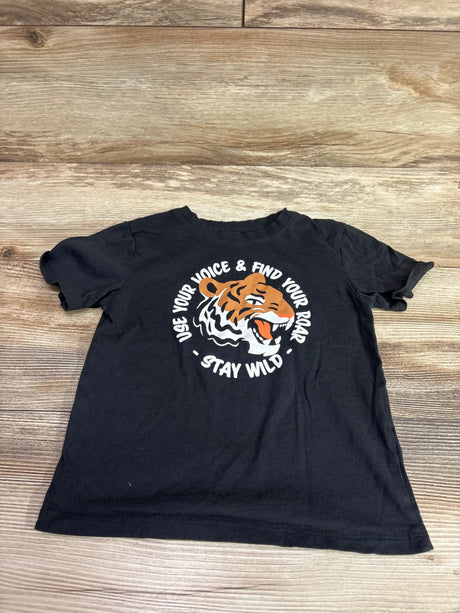 Front view of black H&M tiger shirt with tiger graphic and Use Your Voice, Find Your Roar, Stay Wild text on wood floor