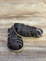 Angled view of brown Salt Water Sun-San sailor sandals with woven straps, buckled ankle strap, and tan sole on wood background
