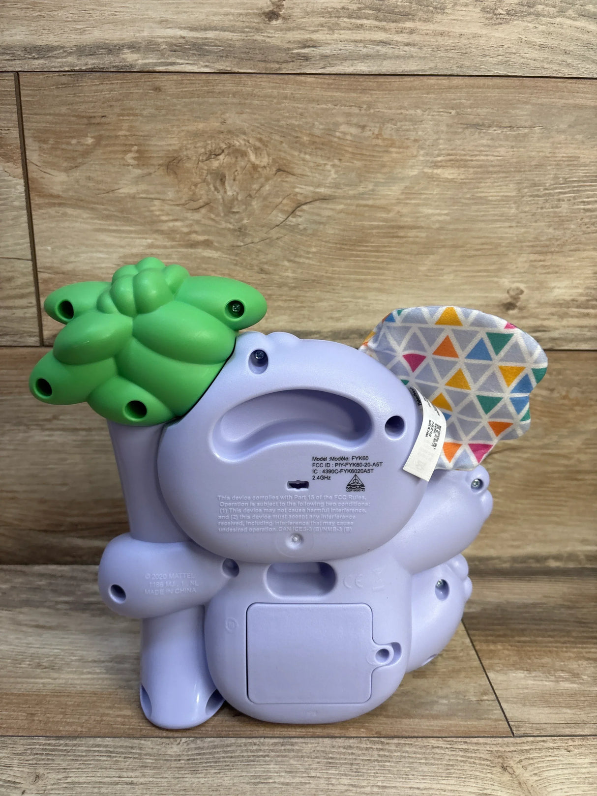 Back view of Linkimals Counting Koala showing battery door, green leaf top and patterned fabric ear on wood background