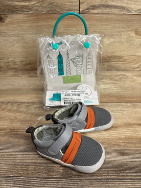 Angled front view of Ro and Me by Robeez gray mesh baby sneakers showing orange elastic strap and velcro tab on wood