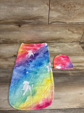Rainbow-colored unicorn baby swaddle blanket and matching hat on wooden floor