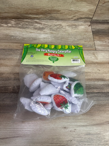 Top-down view of The Very Hungry Caterpillar Storytelling Kit showcasing fruit-themed storytelling pieces in a clear bag on a wood surface