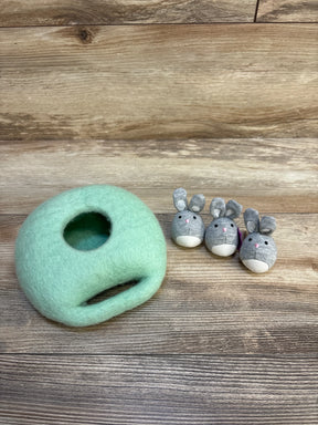 Mint green felted playhouse with three plush gray bunny toys on wood background