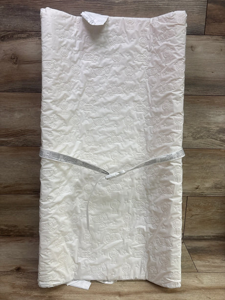 Top view of Serta foam contoured changing pad showcasing an embossed sheep pattern and safety strap on a wood floor