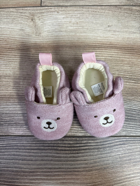 Top view of pink Bearpaw knit bear booties in size 1C showcasing bear-face details and pull tabs on a wood-look surface