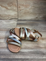 Top front view of metallic faux leather toddler sandals size 7C showing crisscross gold silver and bronze straps and buckle on wood background