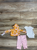Baby clothes set with yellow leaf pattern hoodie, white onesie, and pink pants on wooden floor