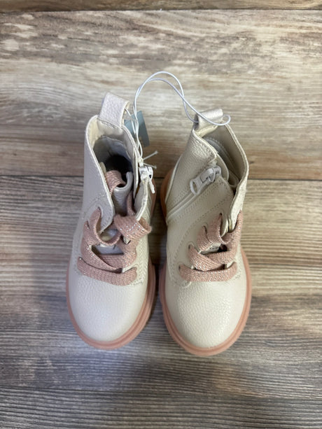 Overhead view of Amaya toddler zipper combat boots in cream and pink showing side zippers and glittery laces on wood floor