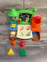 Front view of Fisher-Price Laugh & Learn market showing shape-sorter playset with five fruit pieces on wood background