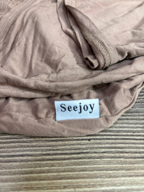 Close-up of brown Seejoy bamboo multi-use car seat and nursing cover showing folded fabric and brand label