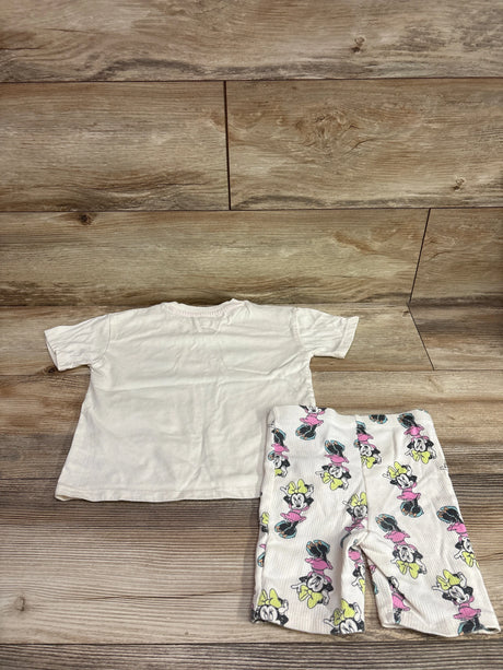 Top view of Disney Junior Minnie Mouse shirt and shorts set with plain ivory shirt and printed shorts on wood flooring
