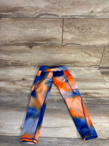 Flat lay of Athletic Works girl's Active Core leggings showcasing orange and blue tie-dye pattern and side pocket on wood floor