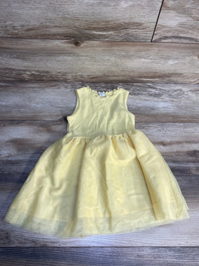 Light yellow sleeveless girls dress with tulle skirt on wooden background