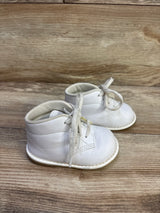 Three-quarter view of Teeny Toes white first-walker baby shoes showing lace-up front, padded collar, and stitched sole on wood background
