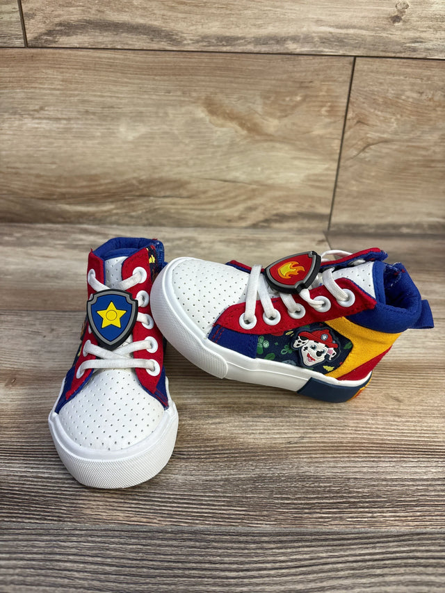 Three-quarter view of Ground Up Paw Patrol high-top sneakers size 6C with white toe, tri-color panels and character badge on wood background