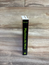 Spine view of Machines At Work board book showcasing vertical green title and author 'Barton' with wood tabletop background