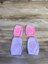 Top view of two pairs of baby crawling knee pads with textured non slip grip on pink and lilac knit, on wood background