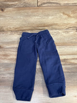 Flat lay of navy toddler drawstring jogger pants showing elastic waistband with drawstring, cuffed ankles, and side pockets on wood background