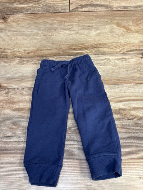 Flat lay of navy toddler drawstring jogger pants showing elastic waistband with drawstring, cuffed ankles, and side pockets on wood background