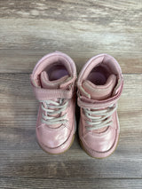 Pair of pink toddler sneakers with white laces and velcro straps on a wooden floor